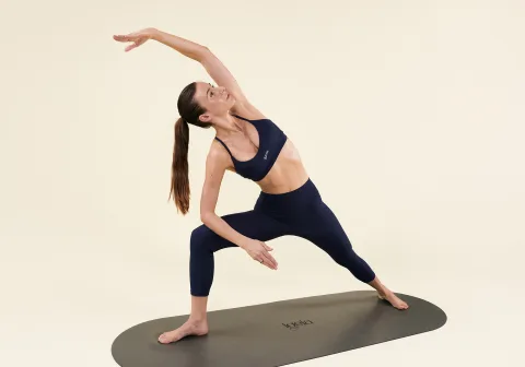 Carlotta Gagna in a side-bend Pilates pose on a yoga mat