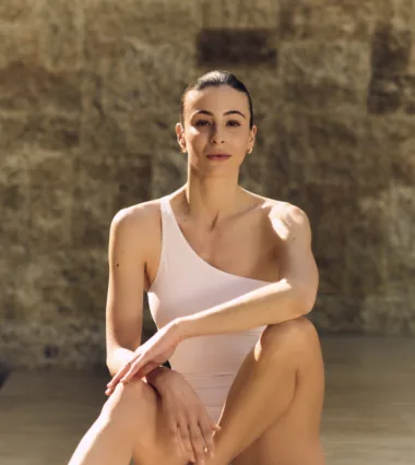 Carlotta Gagna seated, smiling in a one-shoulder leotard