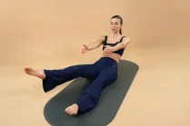 Sessione Addome sgonfio con Carlotta Gagna inclinata all'indietro su un tappetino con una gamba sollevata, l'altra piegata e le braccia protese in avanti in Pilates Linfodrenante® Express