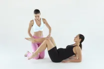 Esercizio di Pilates in gravidanza: Carlotta Gagna guida una donna seduta che solleva le gambe piegate per rinforzare il core, nel programma Pilates Linfodrenante® Gravidanza